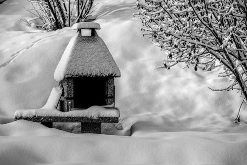 Free A snow-blanketed stone garden ornament amidst a winter scene, capturing the serene beauty of nature. Stock Photo