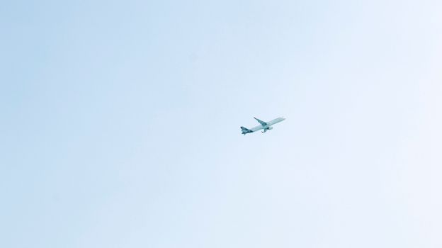 A passenger airplane flies through a clear blue sky, conveying travel and freedom.