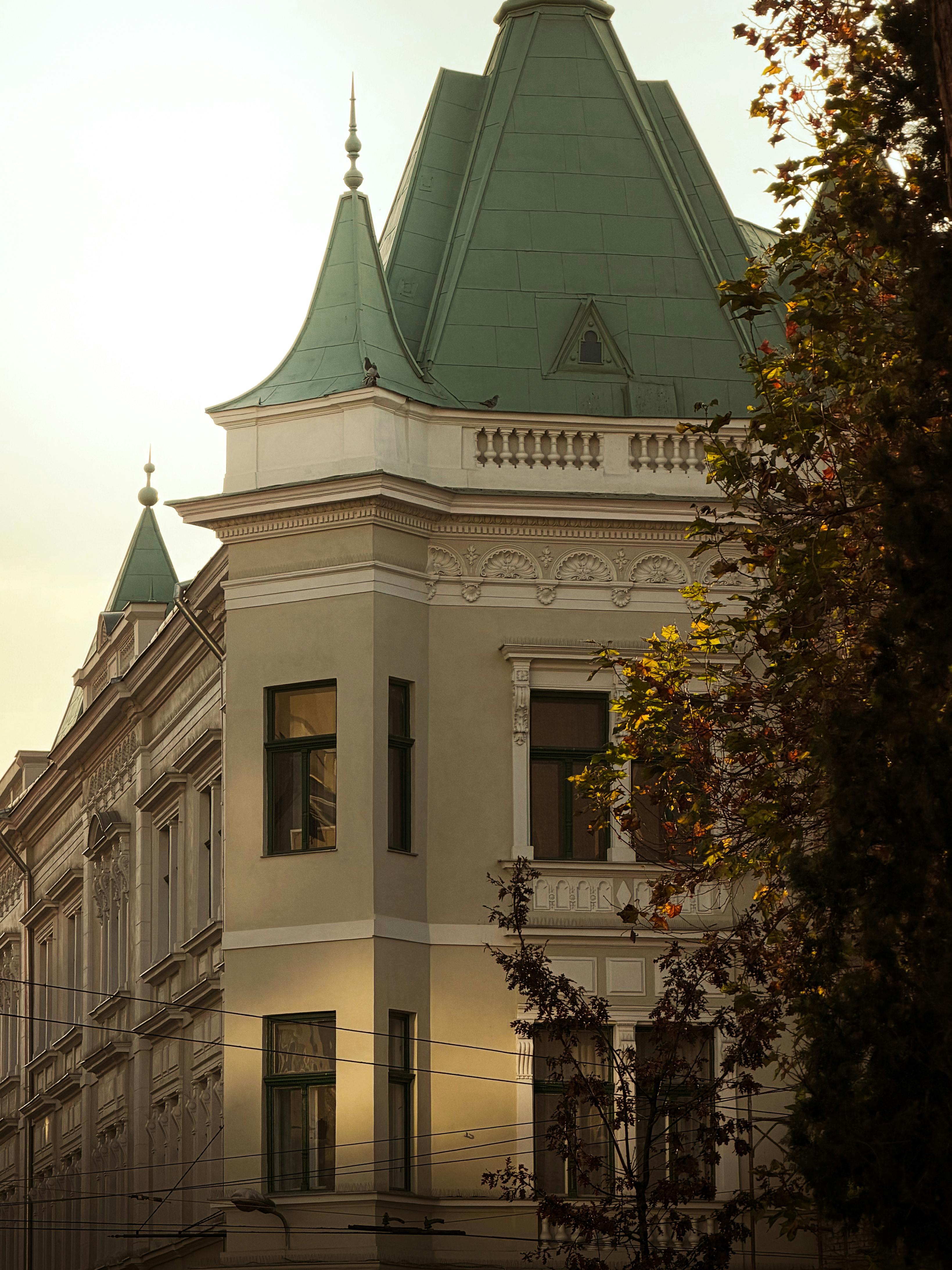 Charming historic building with green spire roofs in Timișoara, Romania, captured in warm daylight.