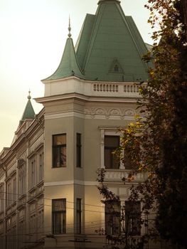 Charming historic building with green spire roofs in Timișoara, Romania, captured in warm daylight.