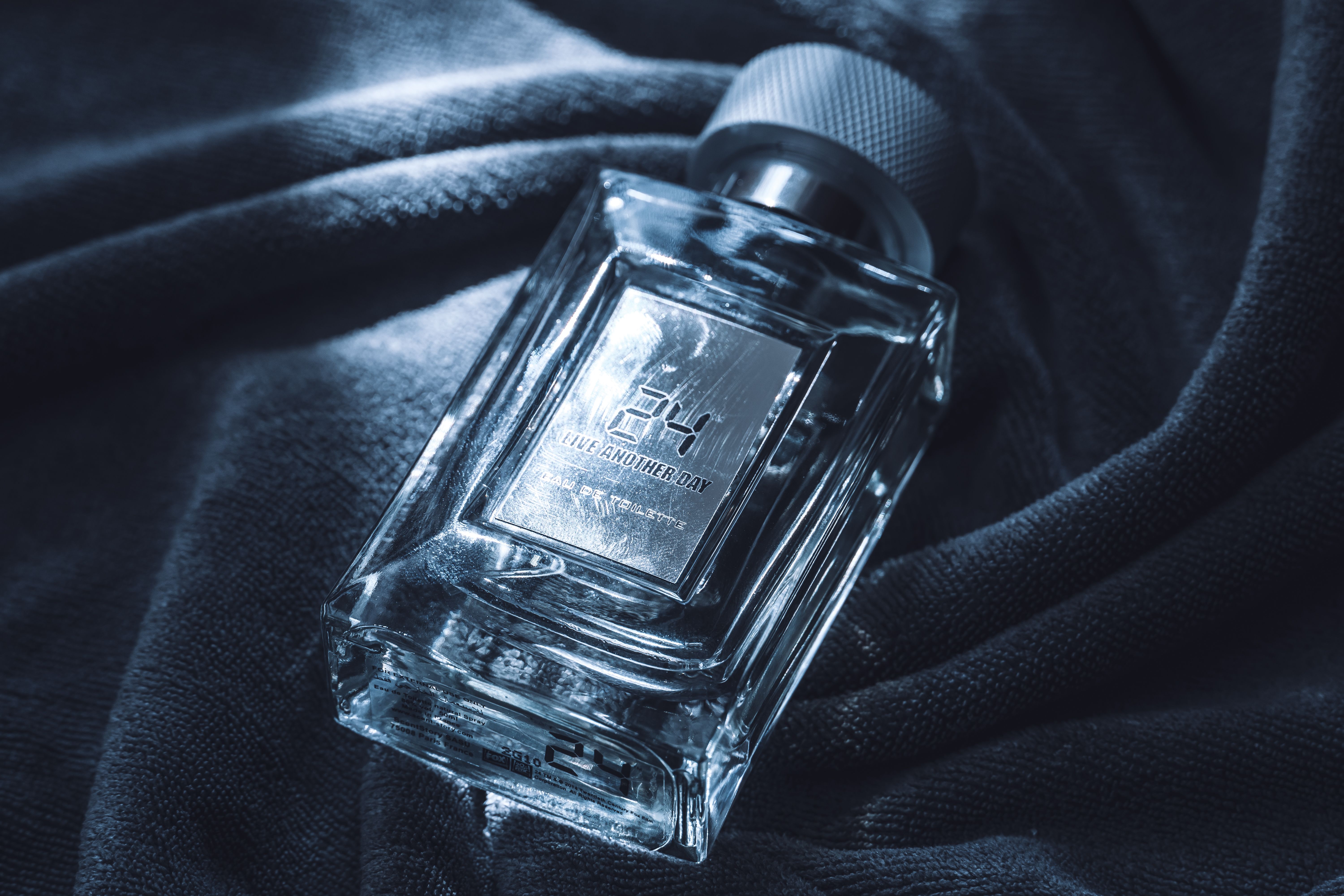 Luxurious glass perfume bottle on dark textured fabric, exuding elegance and refinement.