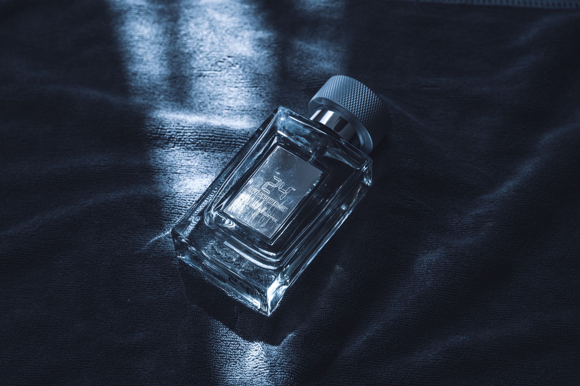 An artistic shot of a luxury perfume bottle resting on textured fabric, emitting sophistication.