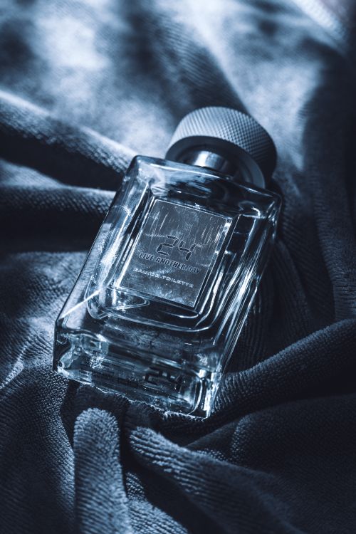 Free A close-up of an elegant glass perfume bottle resting on soft fabric, showcasing luxury and style. Stock Photo