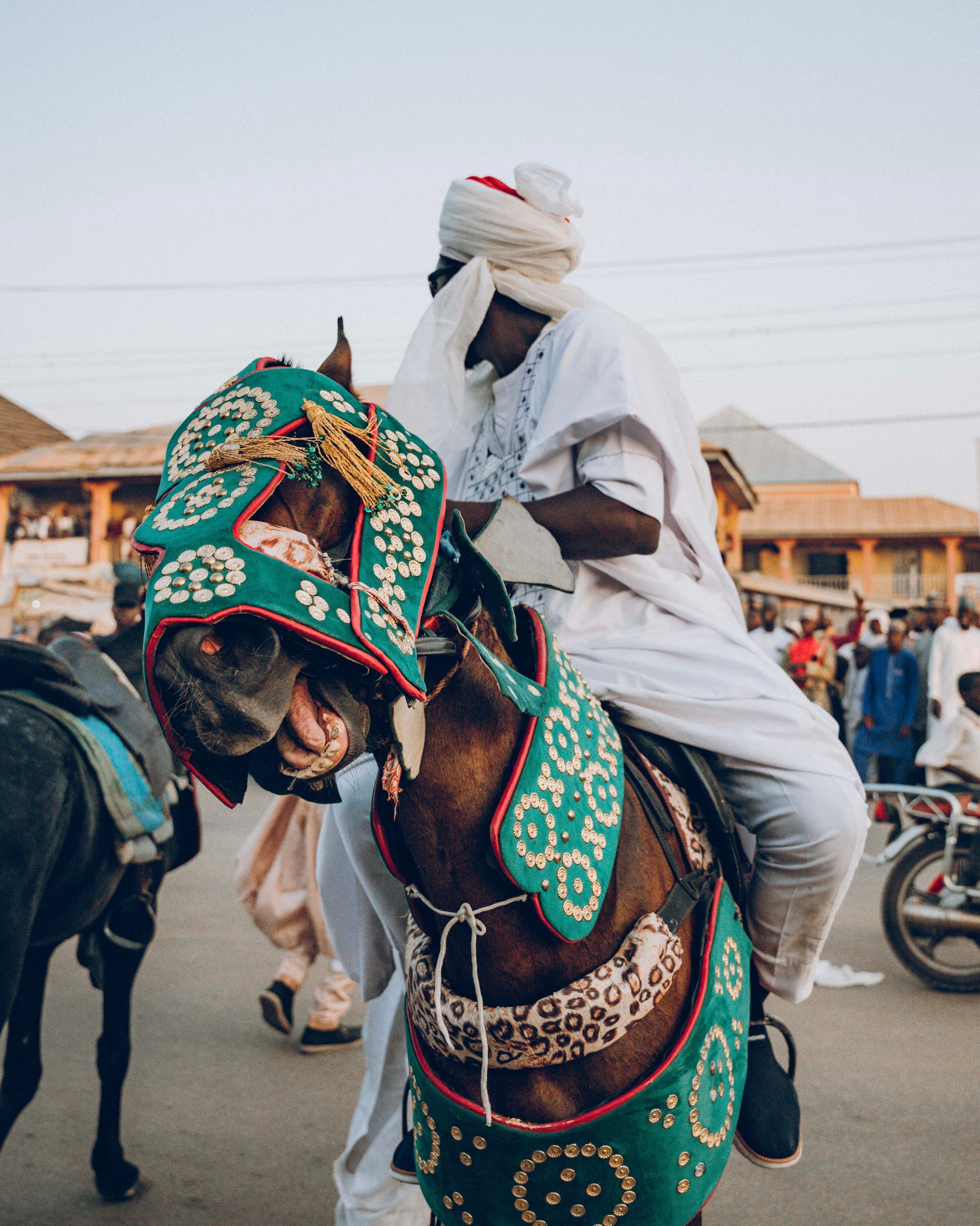 A man in traditional attire riding a beautifully adorned horse at a cultural festival.
