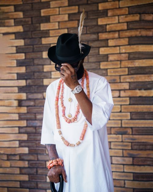 Free Man in white traditional attire with feathered hat and coral beads, classic style. Stock Photo