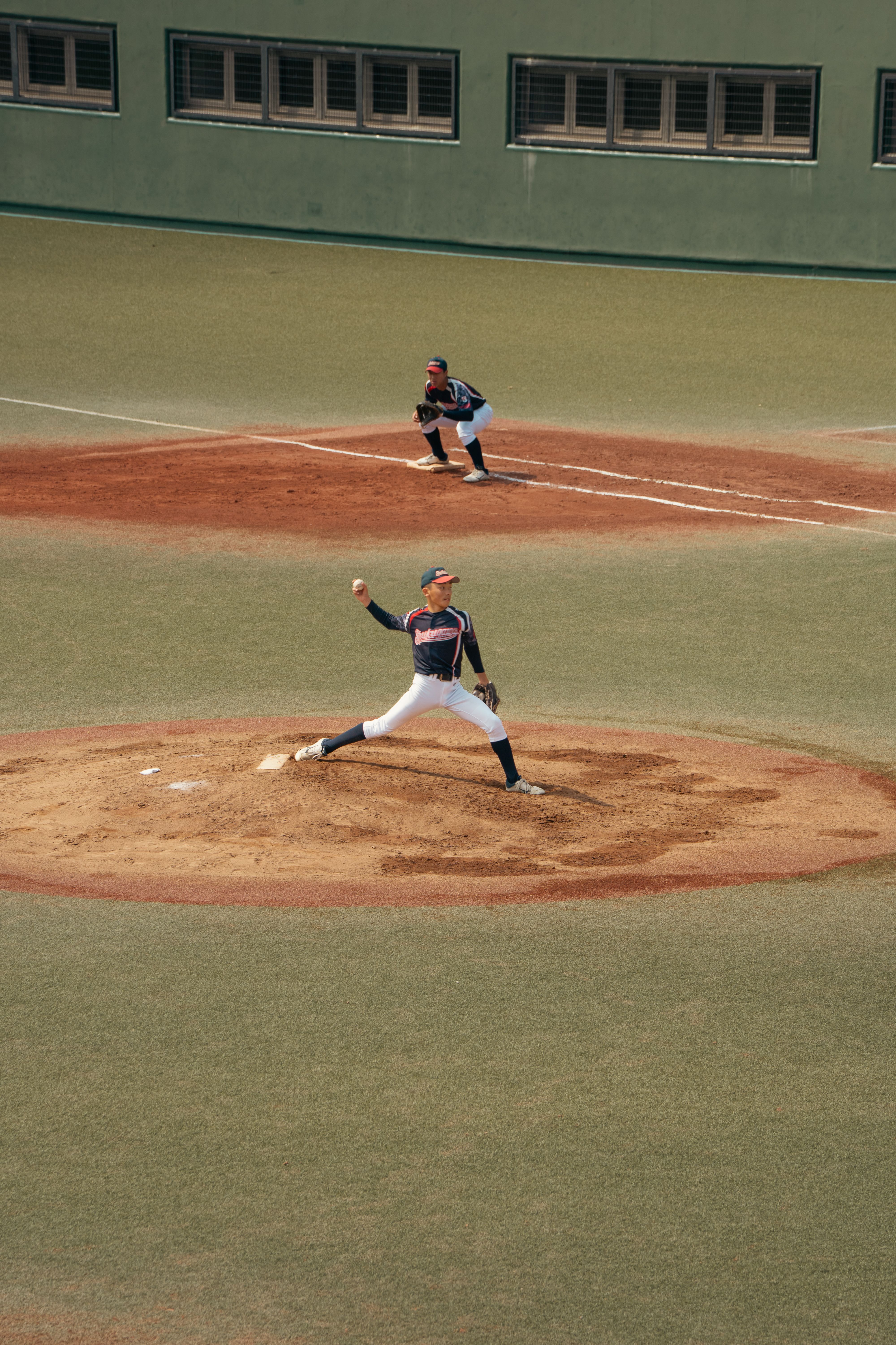 An exciting baseball game with a pitcher and infielder in motion on a Tokyo field.