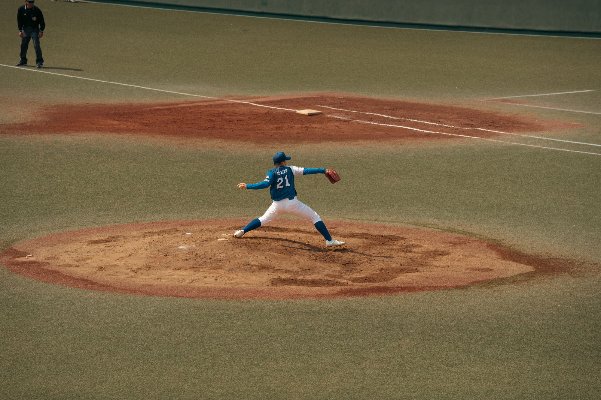 Baseball player mid-throw during a game at a Tokyo baseball field. Capturing the intensity and focus of sports.