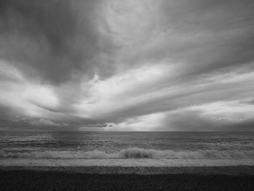 Free Stunning monochrome seascape featuring dramatic clouds and ocean waves, exuding tranquility and power. Stock Photo