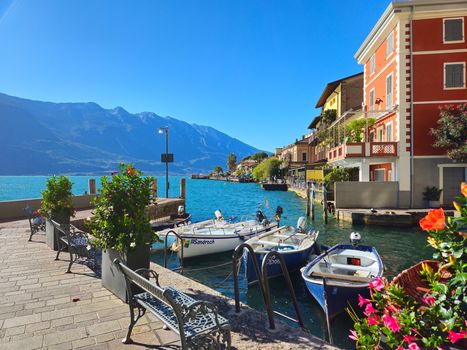 Beautiful view of Limone sul Garda with colorful boats and mountains under a clear blue sky.