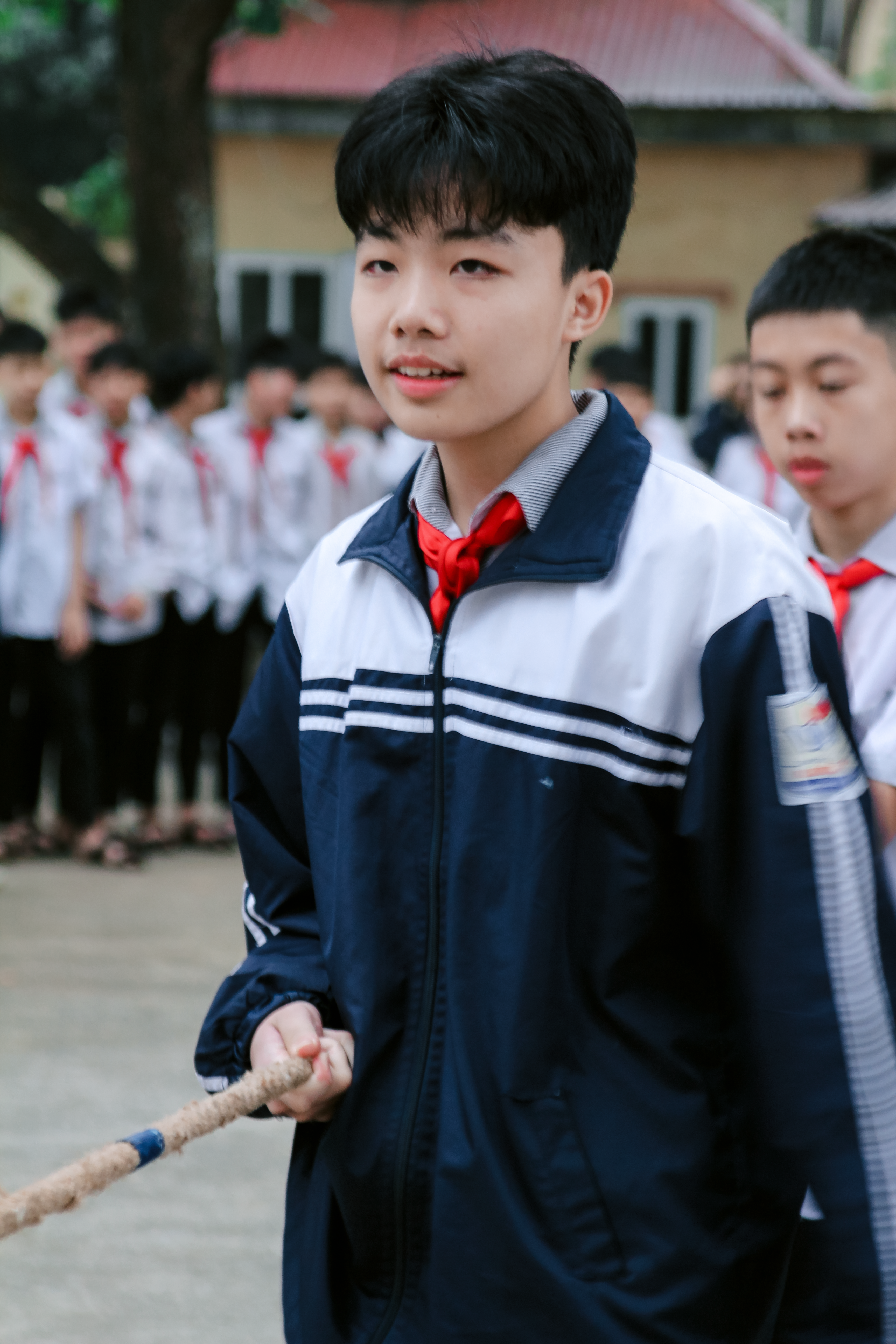 Group of school children engaging in an outdoor tug-of-war competition.