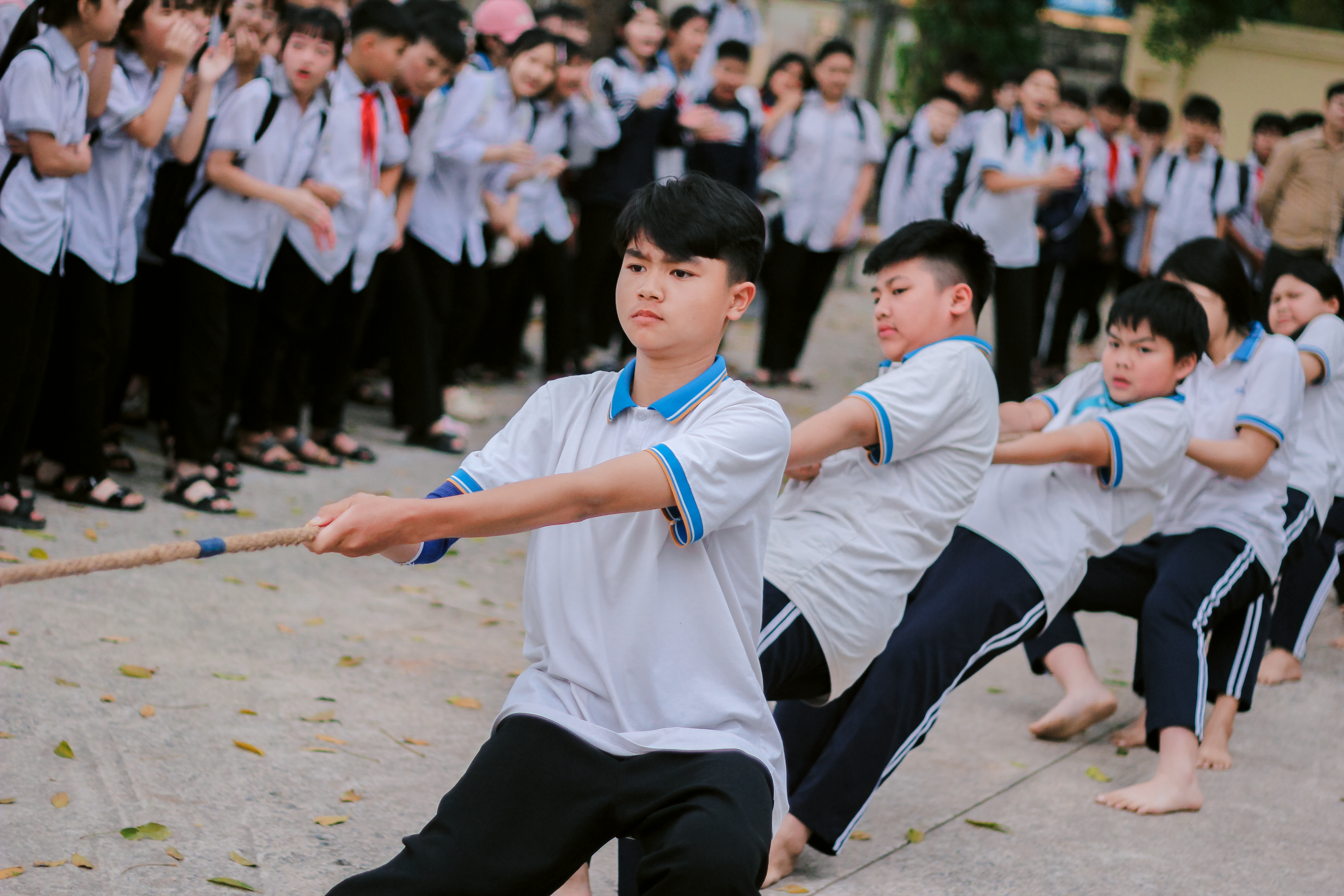 Group of students participating in a competitive outdoor tug-of-war game.