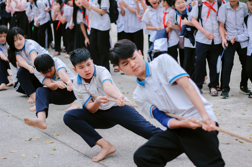 Free A dynamic tug of war game involving enthusiastic schoolchildren wearing uniforms outdoors. Stock Photo
