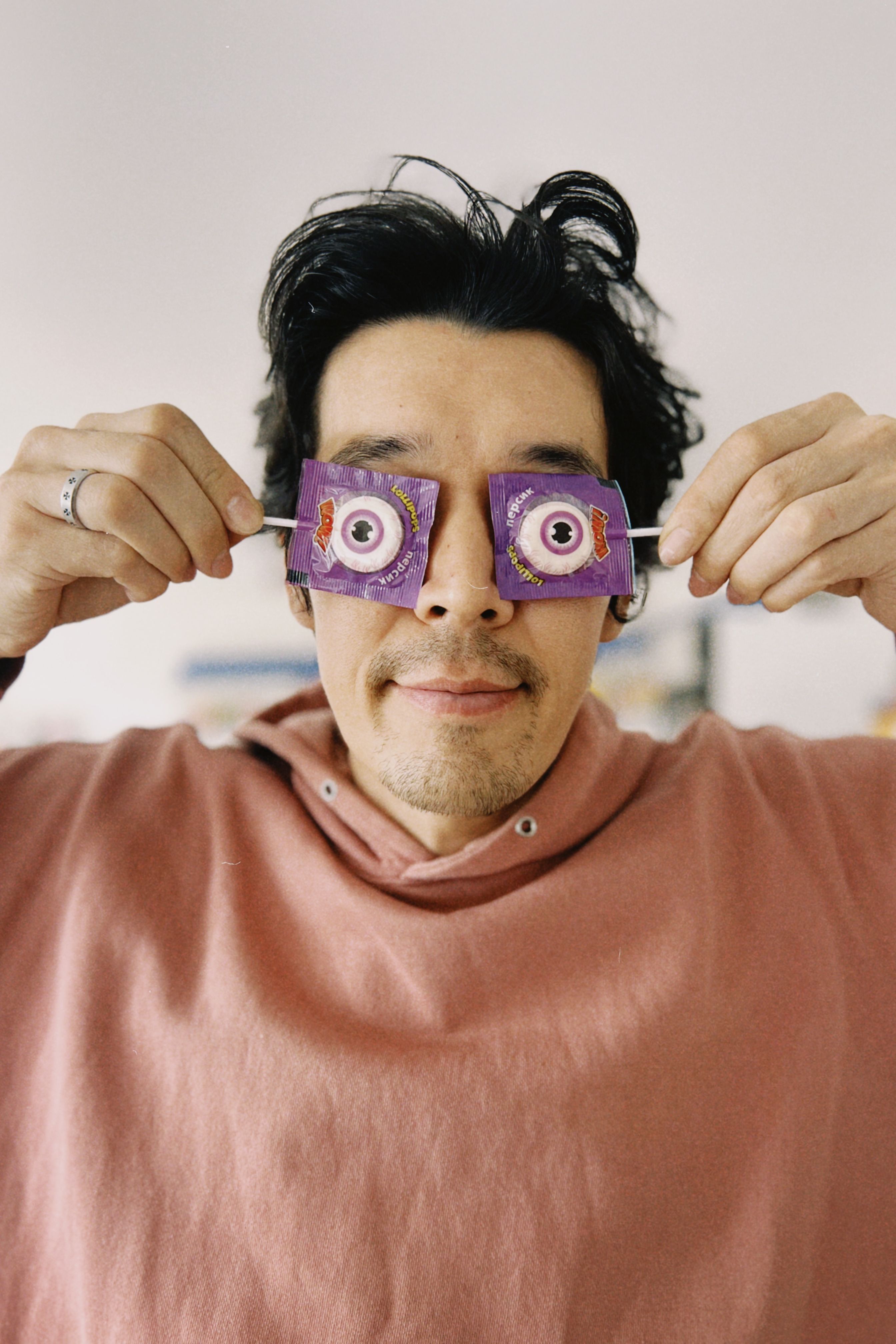 Man making candy glasses with lollipop wrappers on eyes. Fun concept indoors.