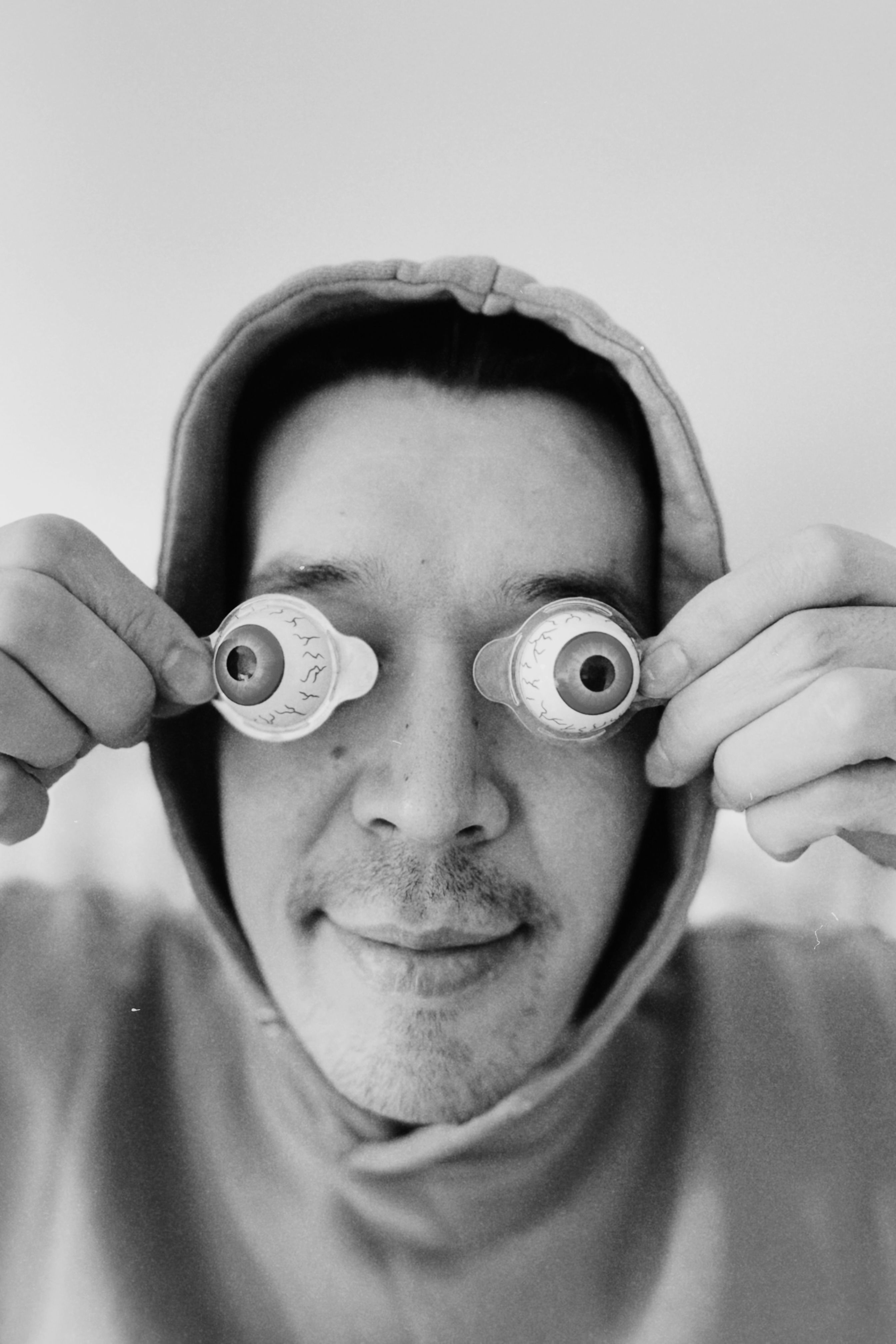 A playful portrait of a man holding fake eyes in a humorous pose, adding a touch of whimsy.