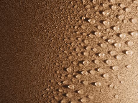 Close-up of water droplets on a textured surface creating a pattern in warm tones.
