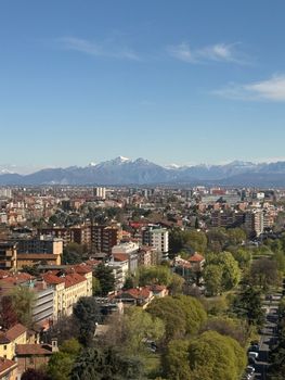 Beautiful aerial view of Milan cityscape with the Alps in the background under a clear blue sky.