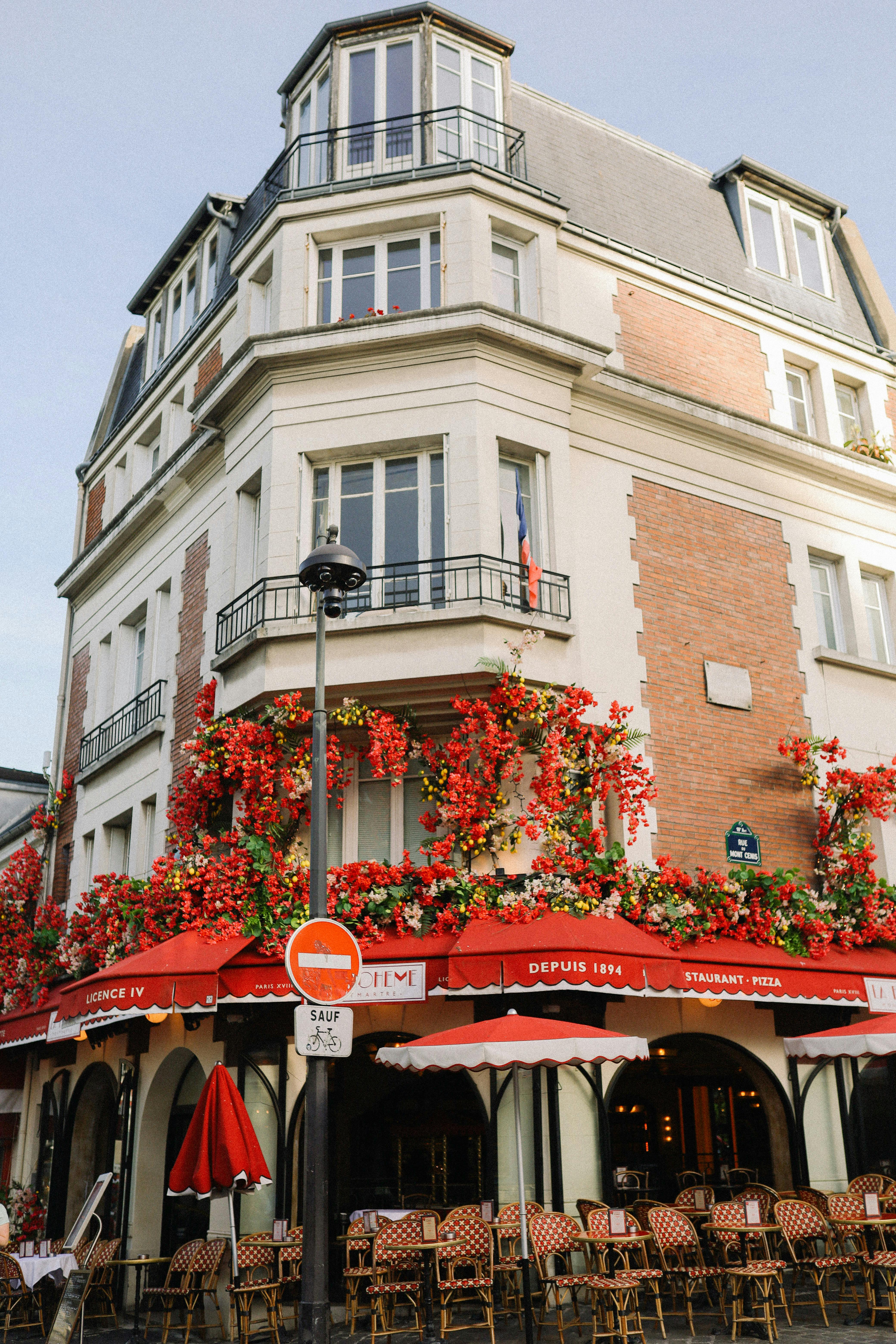 A picturesque Parisian cafe adorned with red flowers and French flags, capturing the essence of Paris.