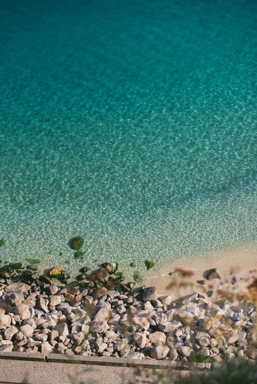 Aerial View of Rocky Shoreline and Clear Blue Sea · Free Stock Photo