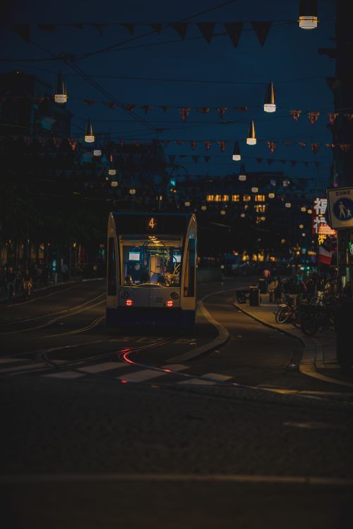 Free A nighttime city tram surrounded by glowing streetlights and festive decorations, capturing urban serenity. Stock Photo