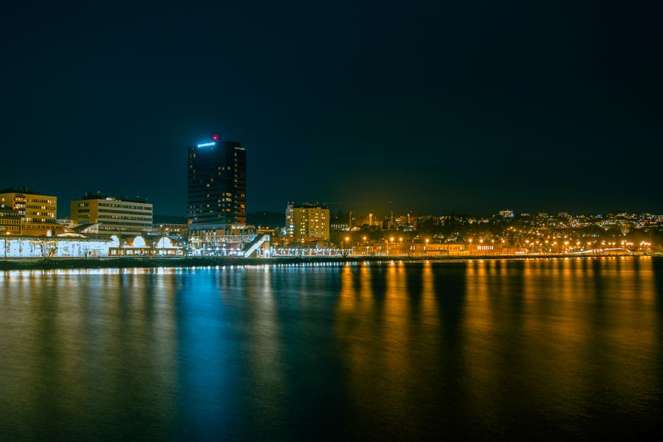 Stunning night view of Jönköping's illuminated skyline reflected in serene lake waters.