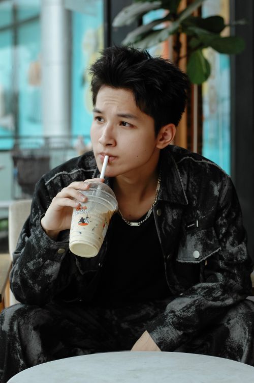 Free A stylish young adult sipping a cool beverage in a trendy cafe setting. Stock Photo
