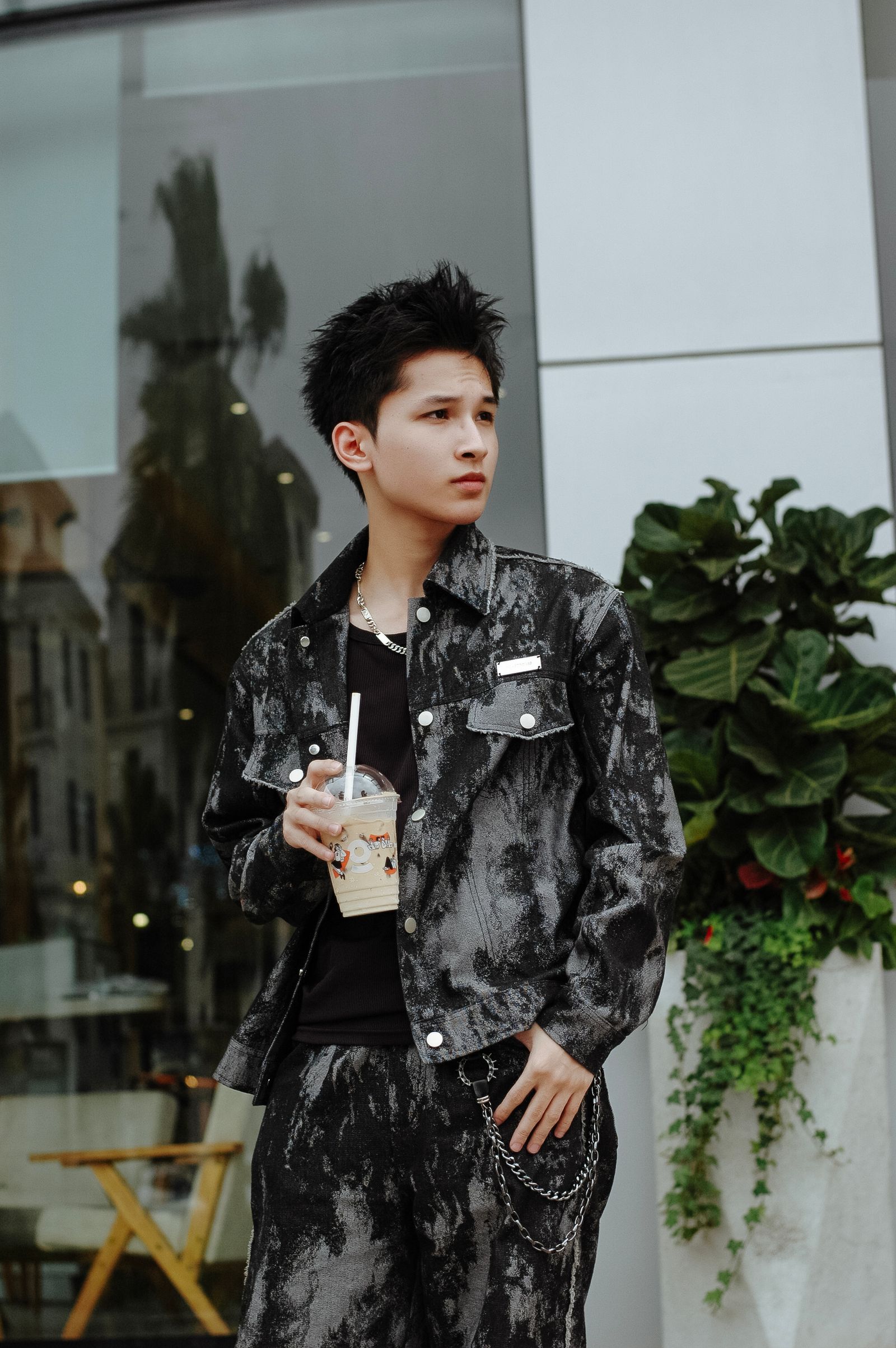 Young adult holding iced coffee outside a modern building