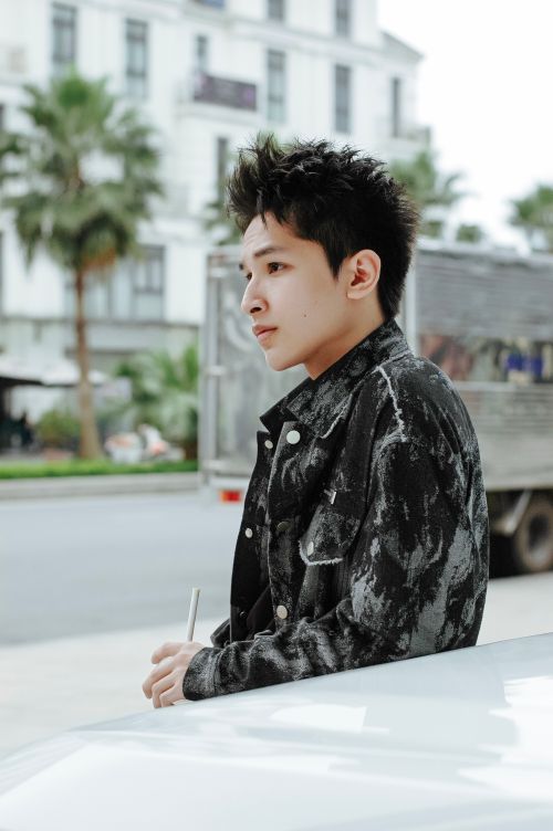 Free Young man in stylish jacket standing outdoors in urban environment, exuding a casual vibe. Stock Photo