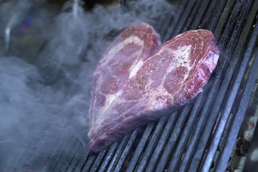 Juicy heart-shaped steak sizzling on a smoky grill, perfect for special occasions.