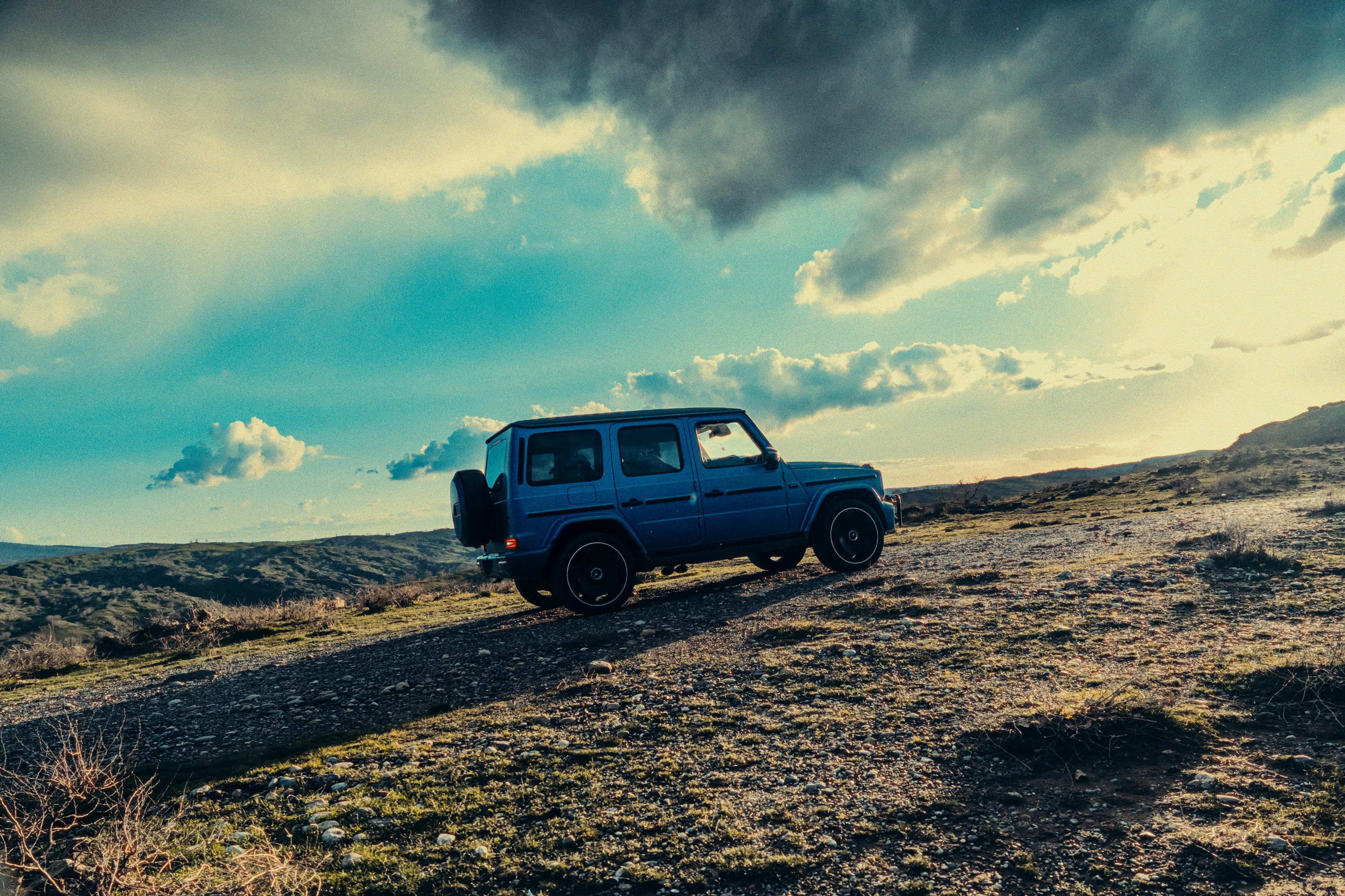 A Mercedes G-Wagon parked on a rugged terrain under a dramatic sky, perfect for lifestyle and automotive themes.