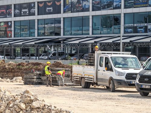 Free Workers unloading materials from a truck at a construction site in front of a car dealership. Stock Photo