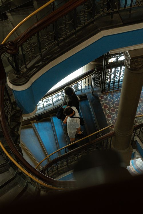 Free Couple descends elegant spiral staircase in a historic building with ornate railings. Stock Photo