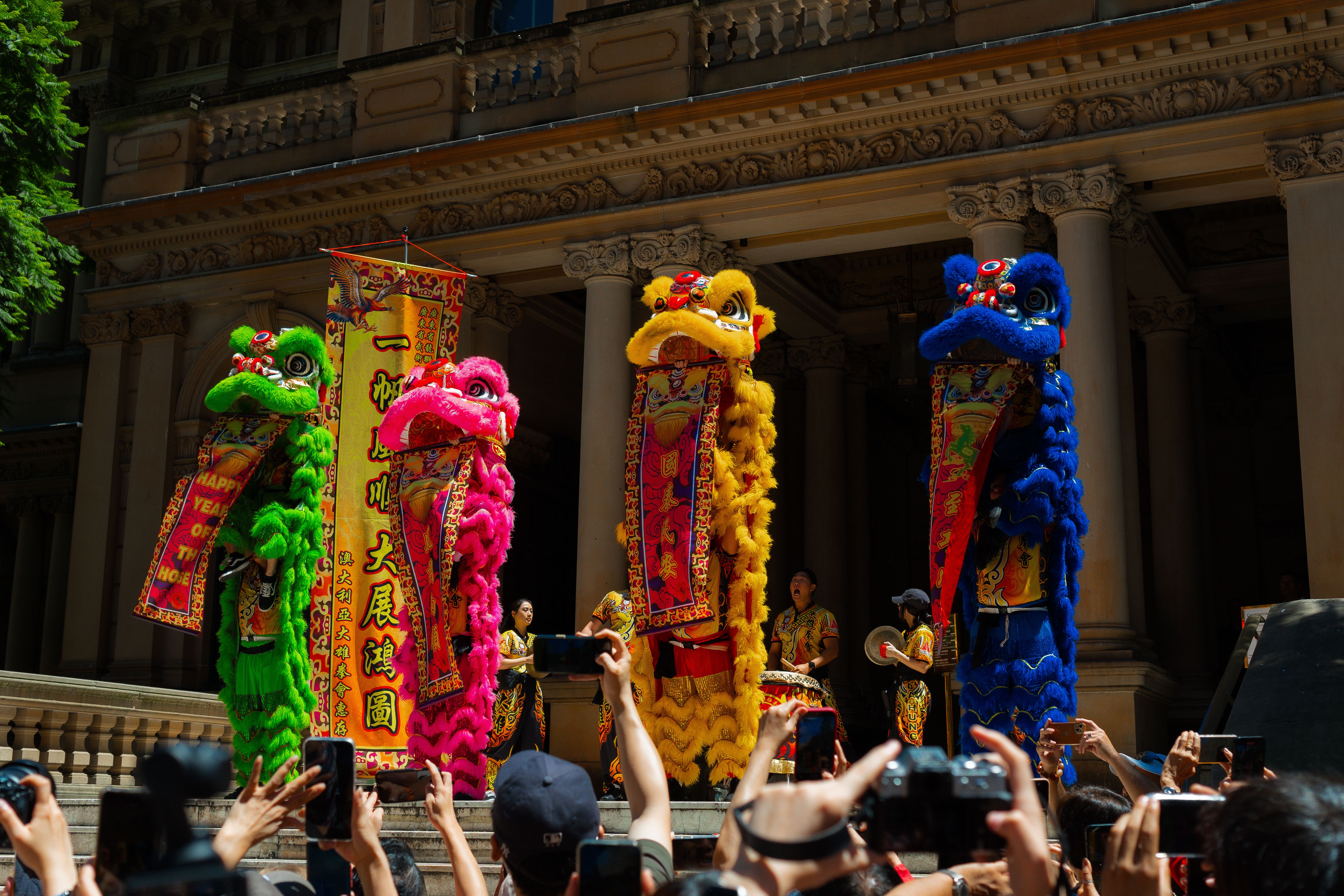 Colorful lion dance performance in Sydney during Chinese New Year celebrations, attracting a large crowd.