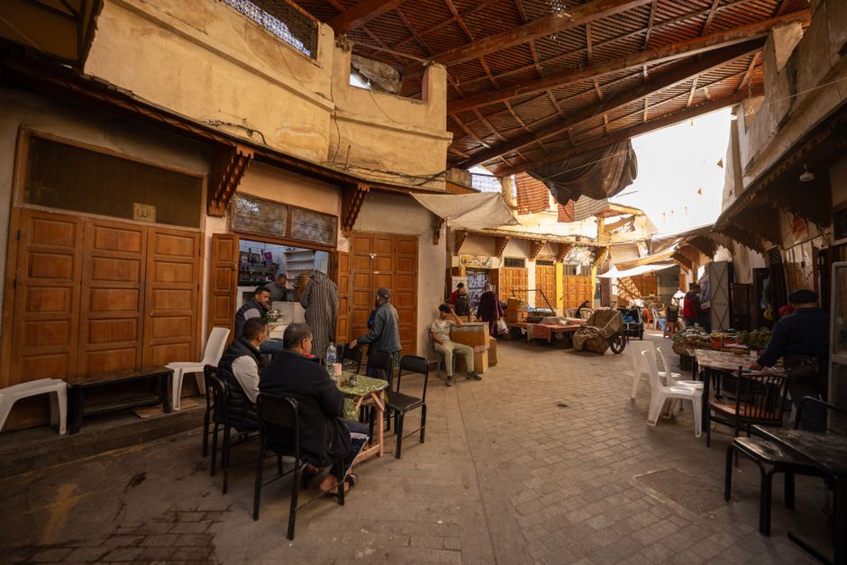 Lively atmosphere of the Fez Medina market in Morocco with people socializing and shopping.