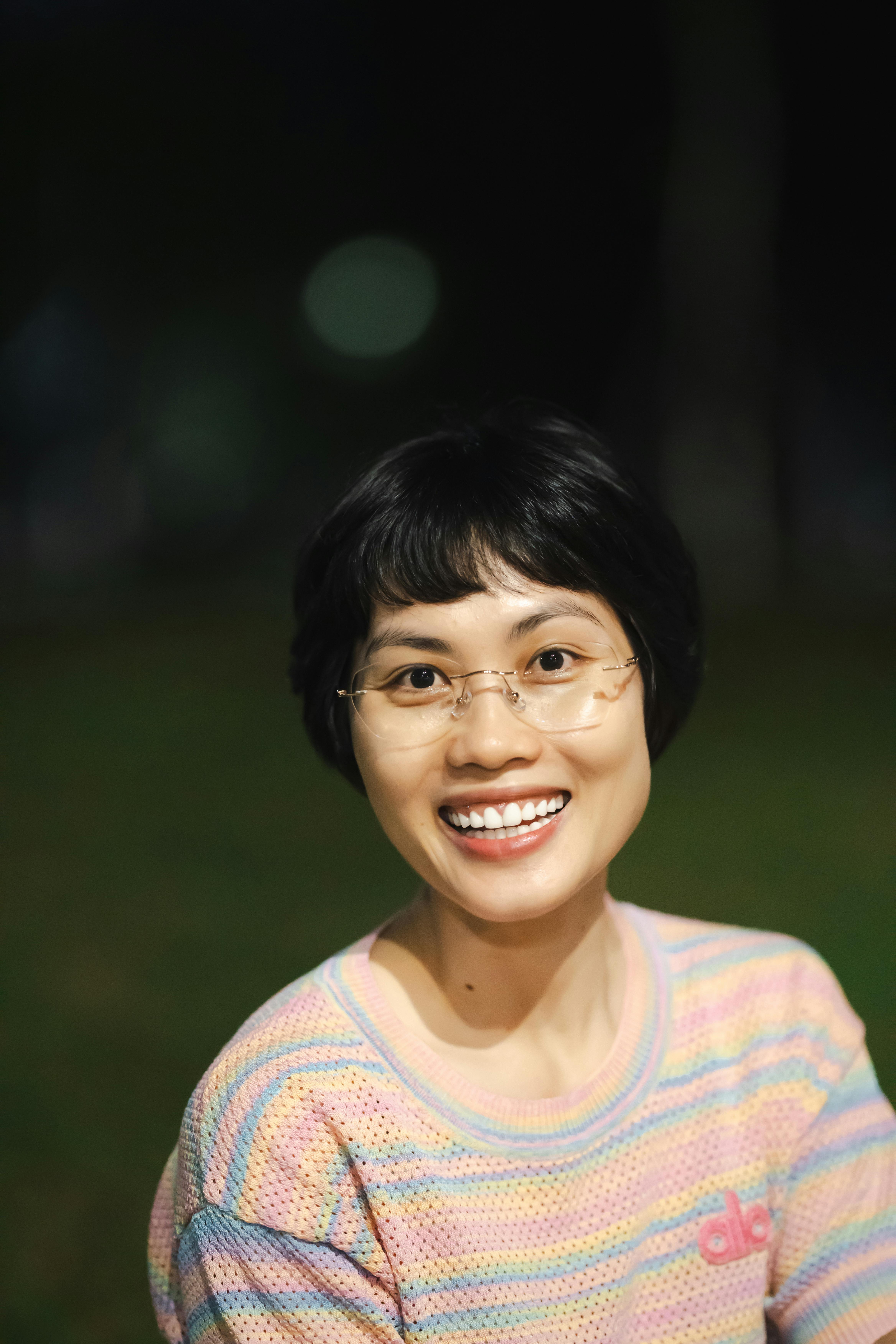 Portrait of a cheerful woman with glasses outdoors at night in Vietnam.