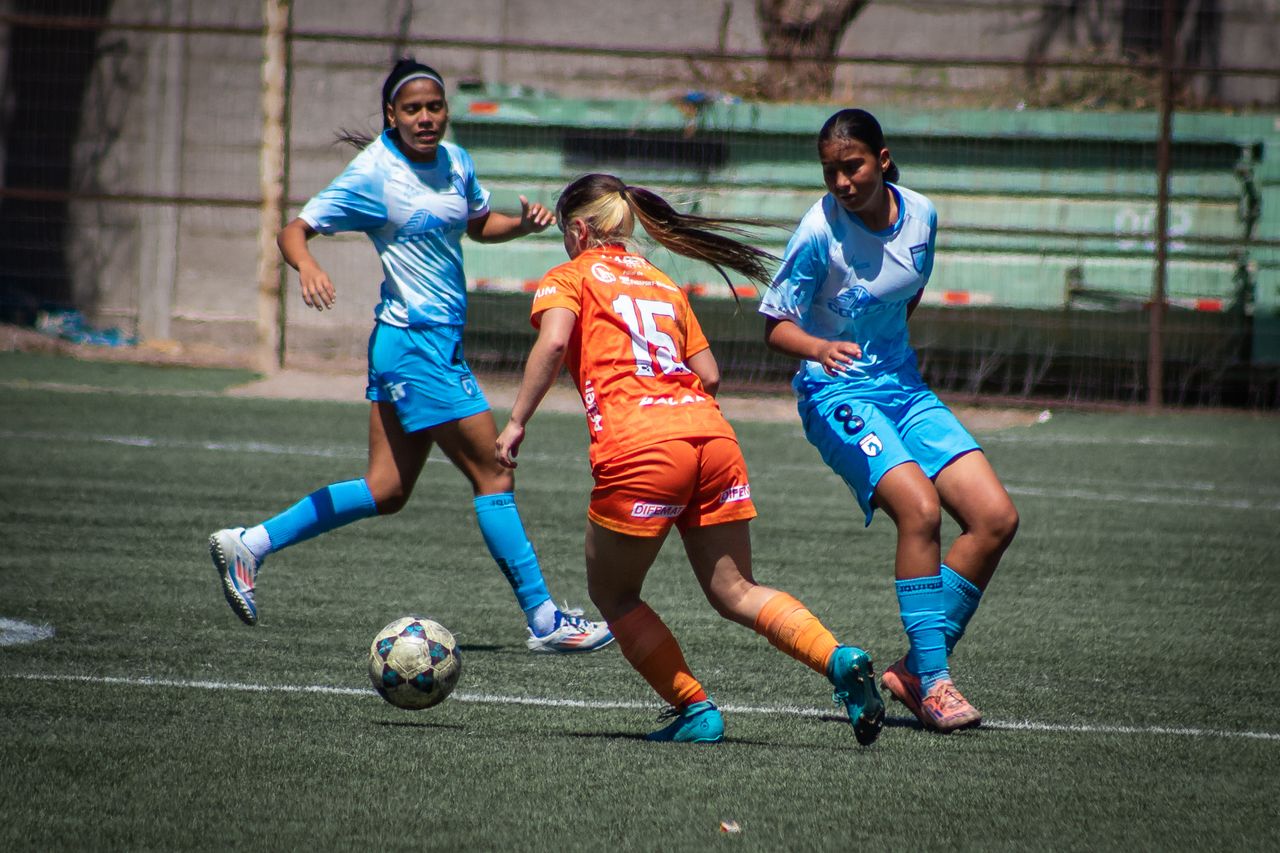 three female soccer players in action on a sunny outdoor field