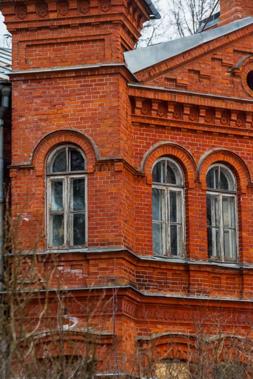 Free Close-up of a historic red brick building facade with detailed arched windows. Stock Photo