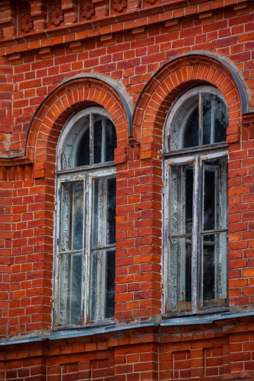 Free Close-up of a vintage red brick building featuring two rustic arched windows. Stock Photo