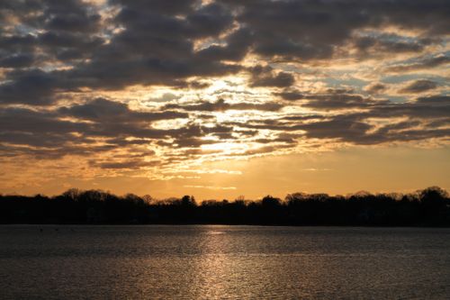 Free A breathtaking sunset with dramatic clouds reflecting on a tranquil lake. Stock Photo