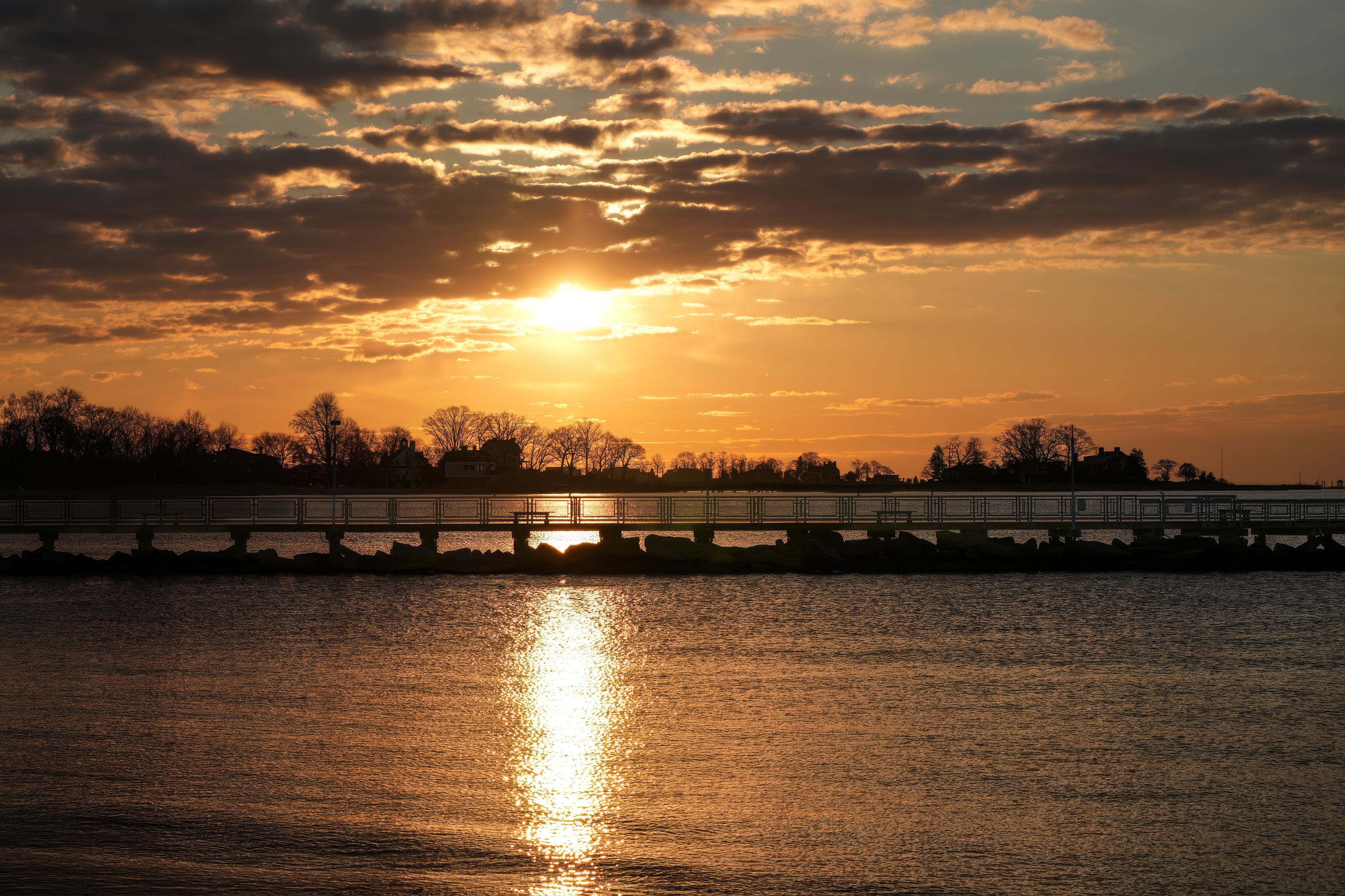 Calm bay water and a pier at sunset, like the Delaware Bay shore where whalers settled Town Bank