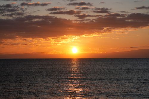 Free Dramatic ocean sunset with vivid orange hues reflecting on the water, creating a serene and warm ambiance. Stock Photo