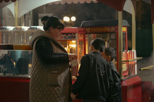 A woman and children buying popcorn at a night market stand in Uzbekistan.