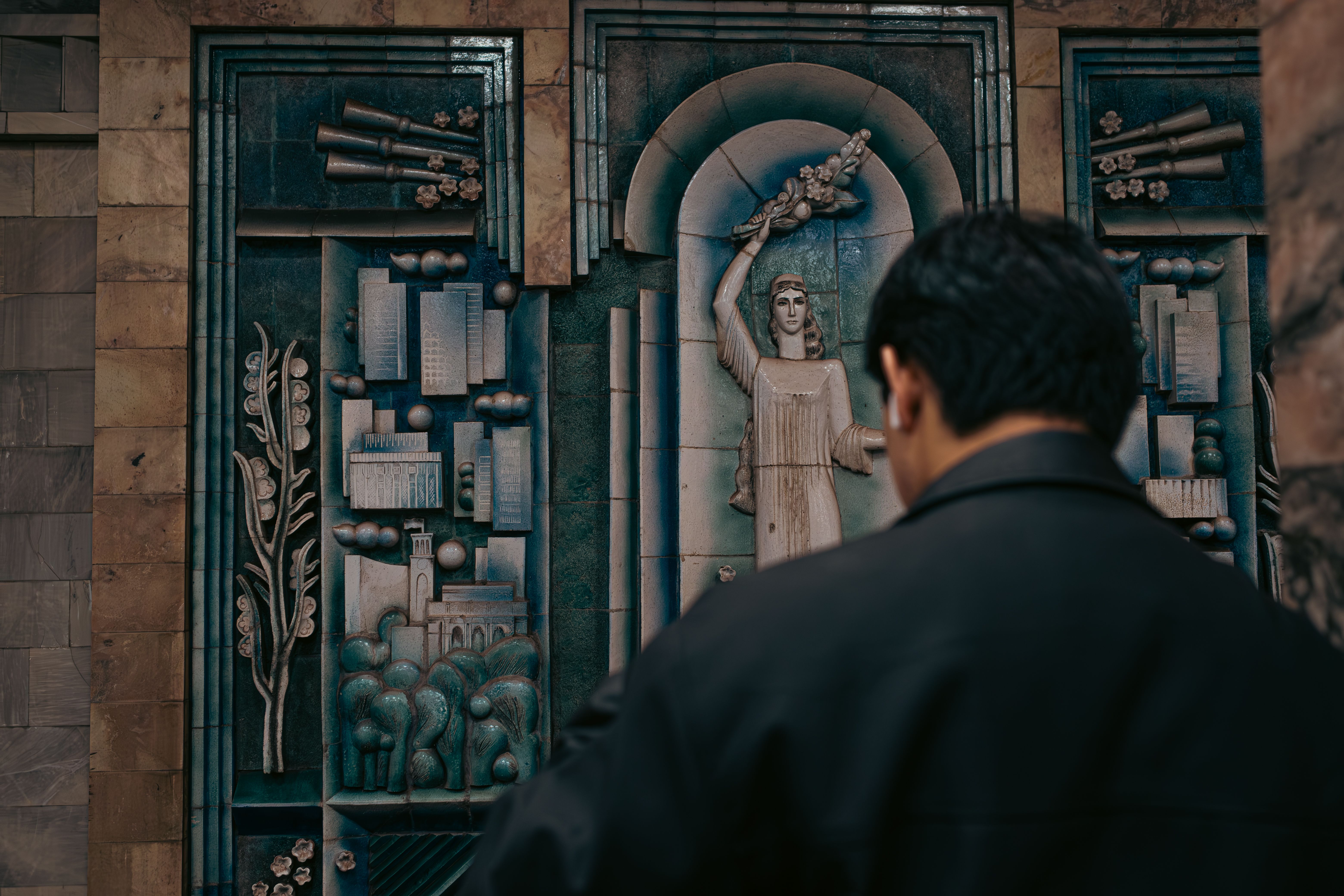 Man Observing Historic Relief Sculpture · Free Stock Photo