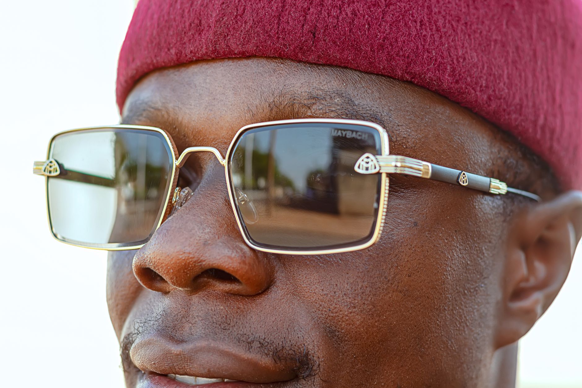 Close-up portrait of a man with stylish sunglasses and a red cap, showcasing modern fashion.