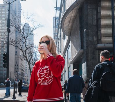 Fashionable woman sipping coffee on a sunny day in downtown Chicago with urban surroundings.
