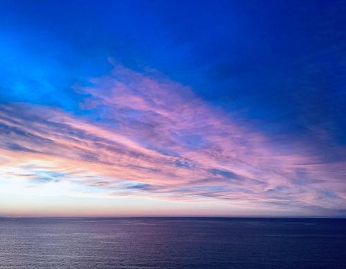 Free Stunning view of a vibrant sunset over the ocean, showcasing dramatic pink and blue clouds. Stock Photo