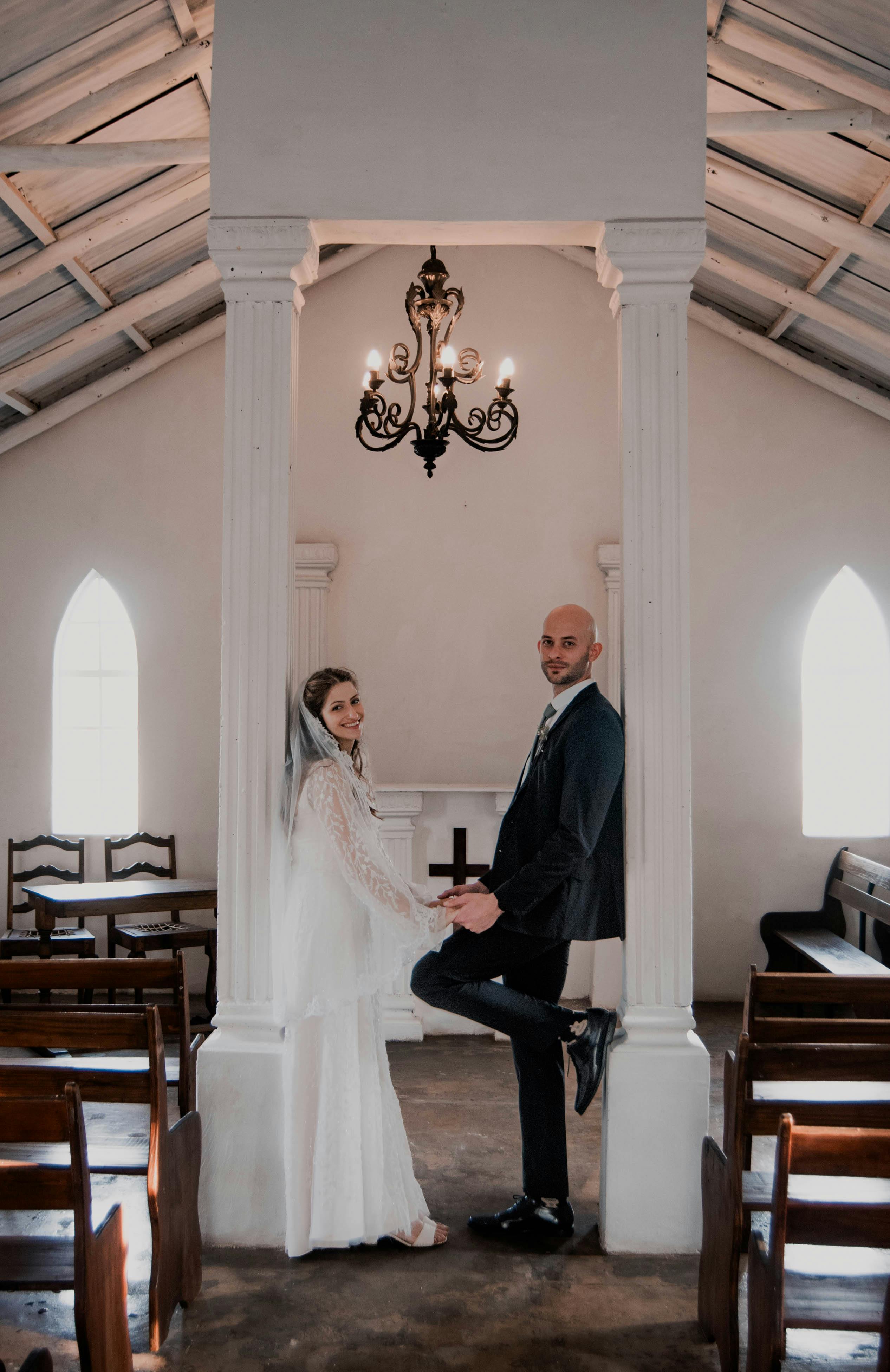 A bride and groom joyfully pose inside a charming chapel, embracing a new journey together.