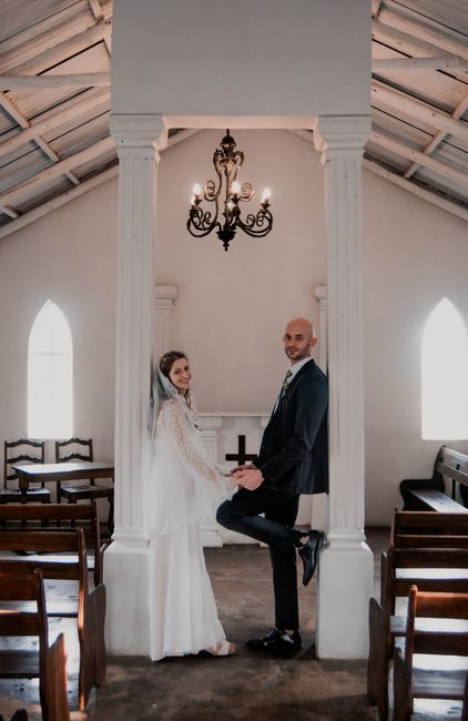 A bride and groom joyfully pose inside a charming chapel, embracing a new journey together.