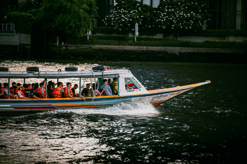 Free Tourists enjoy a boat ride on a Bangkok river, showcasing vibrant culture and water tourism. Stock Photo