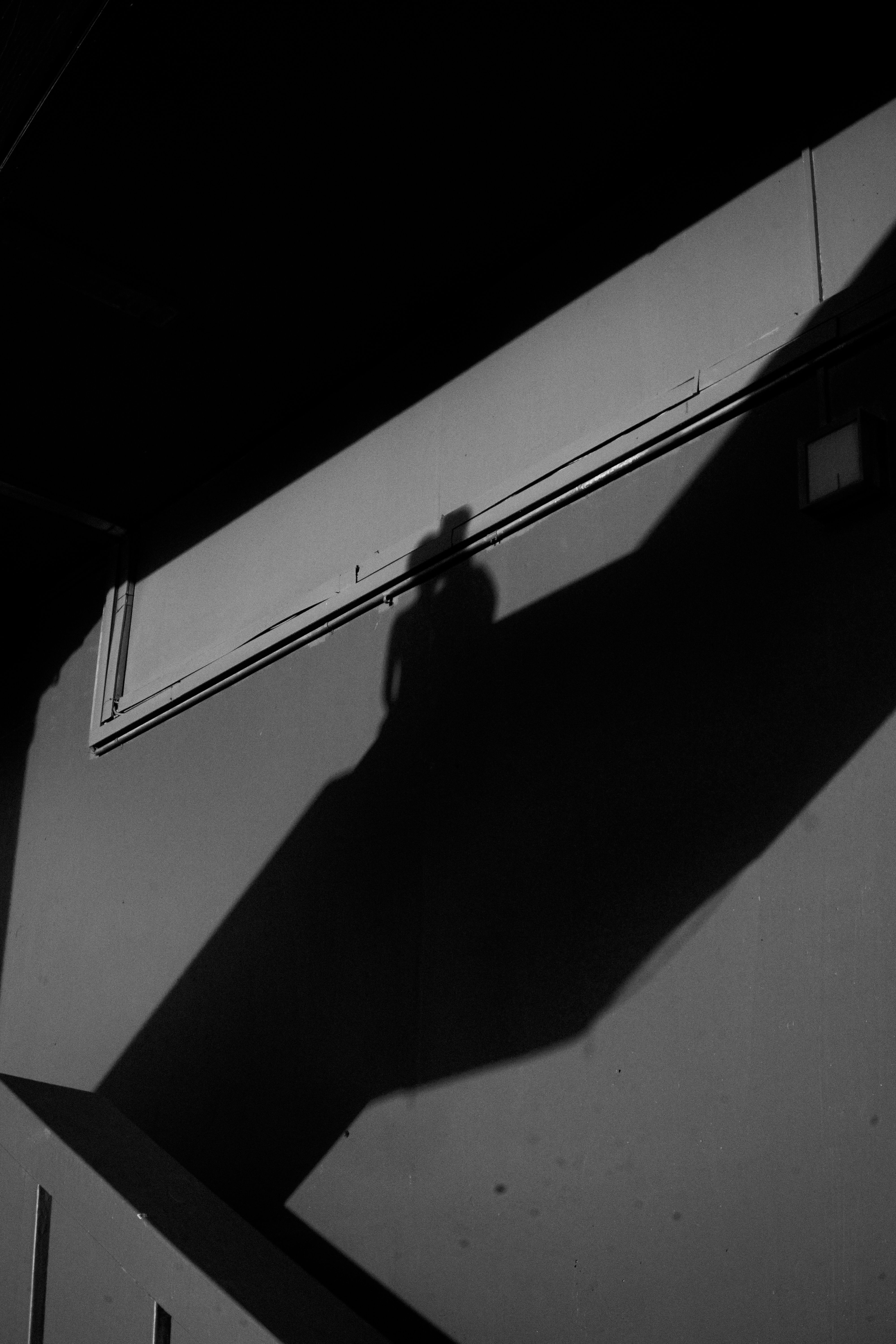 A mysterious silhouette casting a shadow on a wall in a nighttime urban setting.