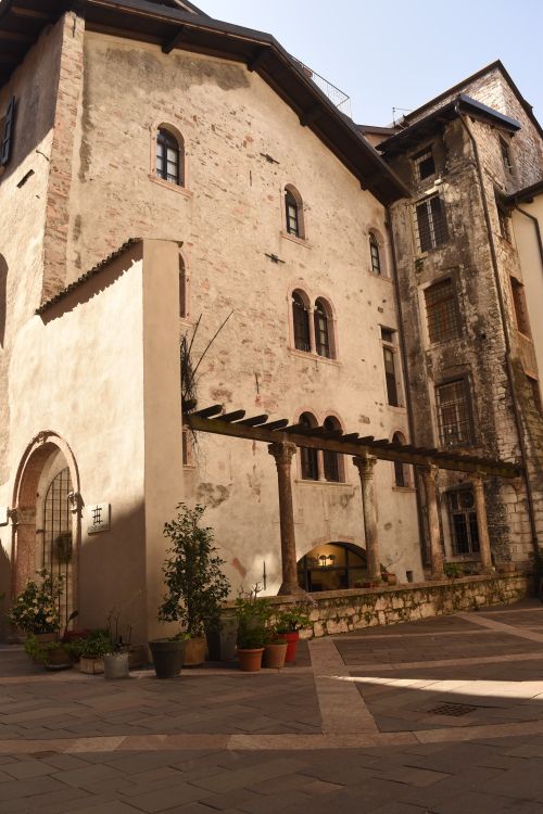 Free Charming old building facade with arch windows and potted plants in Trento, Italy. Stock Photo